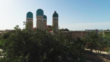 İnsansız hava aracı Chor Minor 'un yakınındaki bir ağacın yanından geçiyor. Khalif Niyaz-kul' un Madrasah 'ı. Eski Buhara, Özbekistan. Güneşli bir gün. Hava Görünümü.
