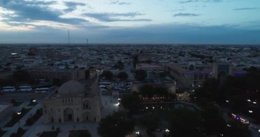Eski Buhara, Özbekistan 'daki evlerle çevrili antik bir Lyab-i Hauz kompleksinin üzerinde bir İHA uçuyor. Bulutlu bir gece. Hava Görünümü.