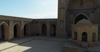 İnsansız hava aracı antik Lyab-i Hauz kompleksinin avlusunda turistlerle birlikte uçuyor. Eski Buhara, Özbekistan. Hava Görünümü.