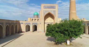Eski bir Ulugbek Madrasah kompleksinin avlusundaki bir grup turistin üzerinde bir dron uçuyor. Eski Buhara, Özbekistan. Hava Görünümü.
