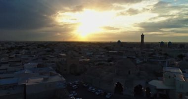Bir dron, günbatımı gökyüzünün arka planında antik bir Lyab-i Hauz kompleksinin üzerinden uçuyor. Eski Buhara, Özbekistan civarında. Hava Görünümü.