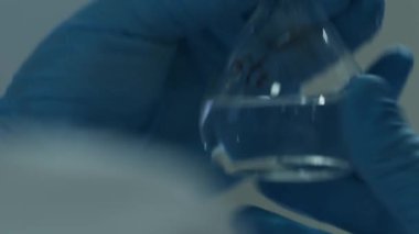 Laboratuvarda cam eşyalar ile çalışan koruyucu giysili laboratuvar teknisyenlerinin elleri. Kapat, Yavaş Hareket.