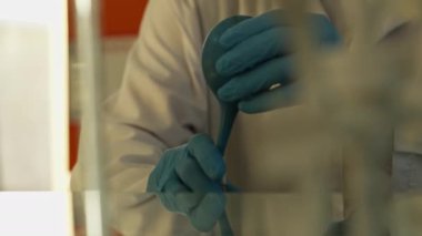 Laboratuvar teknisyeni eldivenler ve koruyucu giysiler içinde laboratuarda pipet ve kimyasal aletlerle çalışıyor. Yavaş Hareket, Kapat.