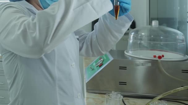 Technik Laboratoryjny Białym Płaszczu Rękawiczkach Ochronnych Wlewa Płyn Naczynia Chemicznego — Wideo stockowe