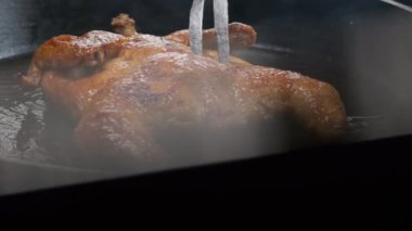Şef ızgara tavuğu büyük bir çatalla çeviriyor, ağır çekimde.