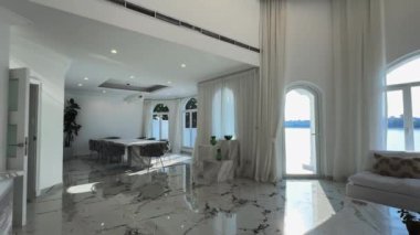 Oturma odasında, özel bir villada. Pencerelerden içeri güneş ışığı giriyor. Yavaş Hareket.