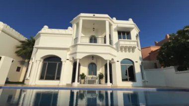 İHA mavi bulutsuz bir gökyüzünün arka planında yüzme havuzu olan özel bir Arap villasının etrafında uçuyor. Hava Görünümü