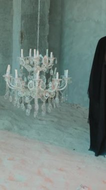 Siyah Arap ulusal elbisesi içinde genç ve güzel bir kadın büyük bir avizenin etrafında yalınayak yürüyor. Yavaş Hareket.