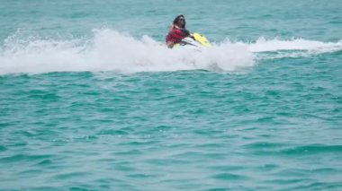 Açık denizlerde jet ski üzerinde can yeleği giymiş esmer bir kadın. Yavaş çekim