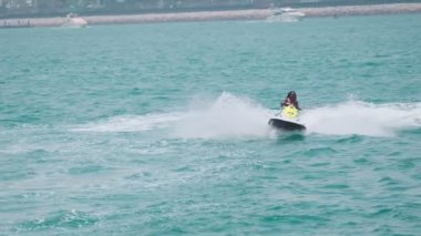 Açık denizlerde jet ski üzerinde can yeleği giymiş esmer bir kadın. Yavaş çekim
