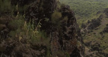 Bir dron, dik bir yamaçta tek kolunda asılı duran genç bir atletik kadın dağcının etrafında uçuyor. Hava Görünümü