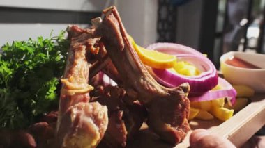Şef pişmiş et, soğan, otlar, domatesler ve sebzelerle servis edilen ahşap bir tahtayı gösteriyor. Kapat, Yavaş Hareket.