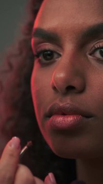 Makyöz, fotoğraf stüdyosunda genç ve çekici bir mankenin dudaklarına ruj sürüyor. Yavaş Hareket.