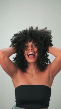 Saçları kıvırcık ve parlak makyajlı gülümseyen genç modelin dikey portresi. Yavaş Hareket, Kapat.