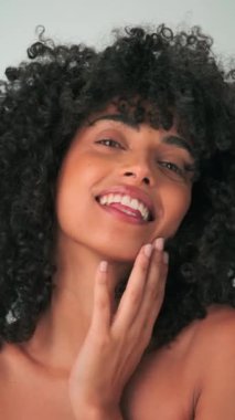 Saçları kıvırcık ve parlak makyajlı gülümseyen genç modelin dikey portresi. Yavaş Hareket, Kapat.