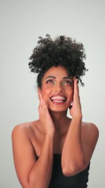 Saçları kıvırcık ve parlak makyajlı gülümseyen genç modelin dikey portresi. Yavaş Hareket, Kapat.