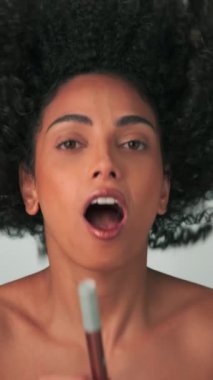 Parlak makyajlı genç bir kadın elinde kozmetik ürünlerle gülüyor ve seviniyor. Yavaş Hareket, Stüdyo Çekimi.