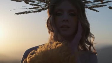 Sonbahar kıyafetleri içinde genç bir bayanın dağlarda gün batımının arka planında çekilmiş fotoğrafı. Odak ön plandan arka plana kayar. Yavaş Hareket