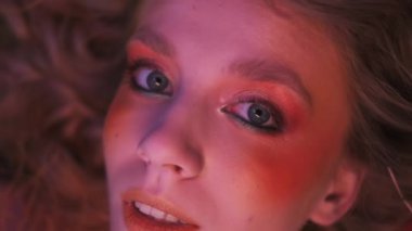 Dallardan, yapraklardan ve mısır başaklarından oluşan sonbahar kıyafeti içindeki genç bir kadının dağınık elmaların arasında çimlerin üzerinde uçarken çekilmiş yakın plan fotoğrafı. Yavaş Hareket.