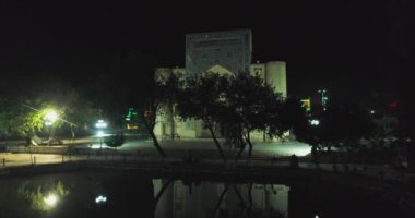 Geceleri Bolo Haouz Camii 'nin önündeki havuzun üzerinde insansız hava aracı. Buhara, Özbekistan, Havadan görünüm.