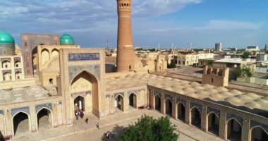 Eski bir Ulugbek Madrasah kompleksinin avlusundaki bir grup turistin üzerinde bir dron uçuyor. Eski Buhara, Özbekistan. Hava Görünümü.