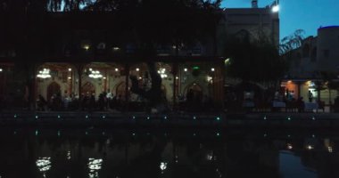 İnsansız hava aracı gece su üzerinde antik Bolo Khauz kompleksinin sütunlarının yanında uçuyor. Eski Buhara, Özbekistan. Hava Görünümü.