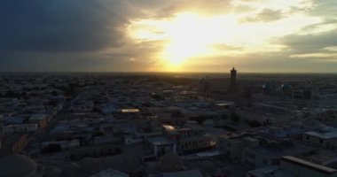 Bir dron, günbatımı gökyüzünün arka planında antik bir Lyab-i Hauz kompleksinin üzerinden uçuyor. Eski Buhara, Özbekistan civarında. Hava Görünümü.