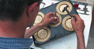 Usta bir kabartma makinesi eski teknolojileri kullanarak bakır plaka üzerinde bir kalıp oluşturur. Buhara, Özbekistan.
