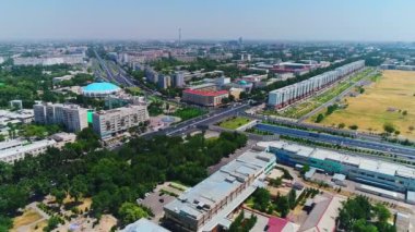 İnsansız hava aracı hareket halindeki arabalarla şehrin yollarında ve otoyollarında uçuyor. Bulutlu bir yaz günü. Hava Görünümü.