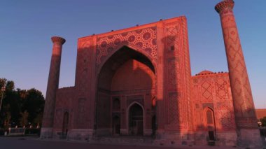 Özbekistan, Semerkant 'taki Bibi-Khanym Camii yakınlarında bir İHA uçuyor. Bina pembe şafak ışığı ile aydınlatılır. Bulutsuz bir sabah. Hava Görünümü.