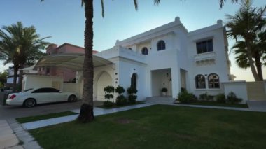 Bulutsuz bir günde Dubai 'de, deniz kenarında palmiye ağaçlarının arasında pahalı bir villanın dışında. Yavaş Hareket.