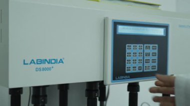 Eldivenli ve koruyucu giysili kimyager laboratuvar mikseri kuruyor. Yavaş Hareket, Kapat.