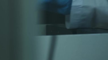 Beyaz önlüklü ve koruyucu eldivenli bir adam bir kimya laboratuvarında bilimsel bir aletle çalışıyor. Yavaş Hareket