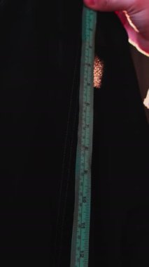 Bir usta atölyesindeki kıyafetlerin uzunluğunu ölçer. Kapat, Yavaş Hareket.