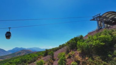 İHA iniş istasyonunun yakınındaki dağ kablosunun üzerinden uçuyor. Güneşli bir yaz günü, çevresi yeşilliklerle kaplı tepelerle çevrili. Hava Görünümü.