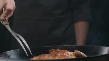Şef ızgara tavuğu büyük bir çatalla çeviriyor, ağır çekimde.