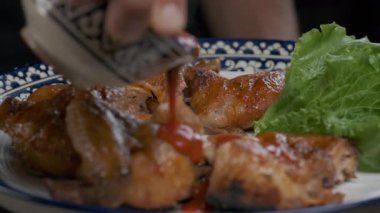 Aşçı ağır çekimde servis edilen ızgara tavuğun üzerine sos döker.
