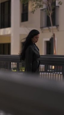 Saçları rüzgarda uçuşan, akşam yürüyüşünde uzun bir yağmurlukla genç bir kadın. Yavaş Hareket