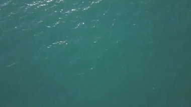 Gün batımında bir dron bir dağ gölünün üzerinde uçar. Bir tekne suda yüzer. Bulutsuz bir yaz akşamı. Hava Görünümü.