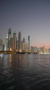 Gece Dubais gökdelenlerinin panoramik manzarası ve geçen bir yattan deniz manzarası. Yavaş Hareket