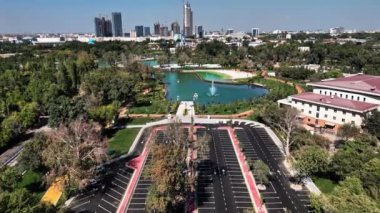 Ağaçları olan bir şehir parkında ve arabalar için park alanı olan bir İHA. Güneşli bir yaz günü. Hava Görünümü, Yavaş Hareket