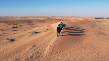 Çöl kum tepecikleri boyunca yürüyen bir grup turist üzerinde bir dron. Dubai, güneşli bir yaz günü. Hava Görünümü