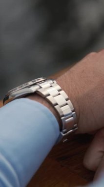 Lüks kol saati olan iş elbiseli genç bir adam pahalı bir premium arabanın yanında duruyor. Dubai 'de bulutlu bir akşam. Kapat, Yavaş Hareket