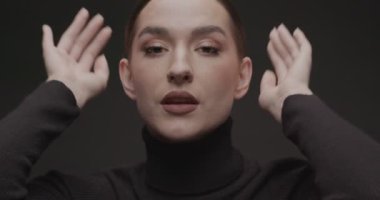 Stüdyoda siyah arka planda genç bir kadının portresi çekiliyor. Yavaş Hareket.