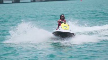 Açık denizlerde jet ski üzerinde can yeleği giymiş esmer bir kadın. Yavaş çekim