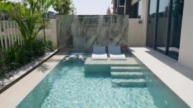 Güneşli bir günde Dubai 'de lüks bir villanın arka bahçesinde küçük özel bir yüzme havuzu. Dışarıda, Yavaş Hareket.