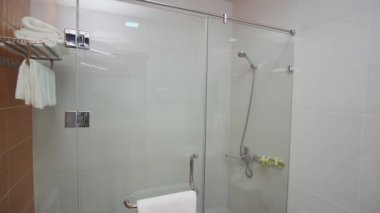 Küçük, rahat bir otelin duş kabininde. Lavabo, tuvalet, havlu, bornoz..