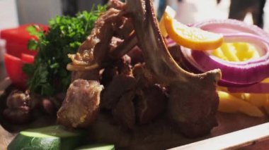 Şef pişmiş et, soğan, otlar, domatesler ve sebzelerle servis edilen ahşap bir tahtayı gösteriyor. Kapat, Yavaş Hareket.