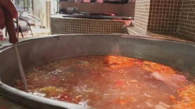 Şef, et çorbasını büyük bir kazanda sebzelerle karıştırıyor. Yavaş Hareket, Kapat.