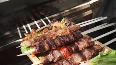 Bir garson ahşap tepsiyi tavuk, et ve ciğer kebabıyla gösteriyor, soğan, bitki ve sebzelerle servis ediliyor. Yavaş Hareket, Kapat.